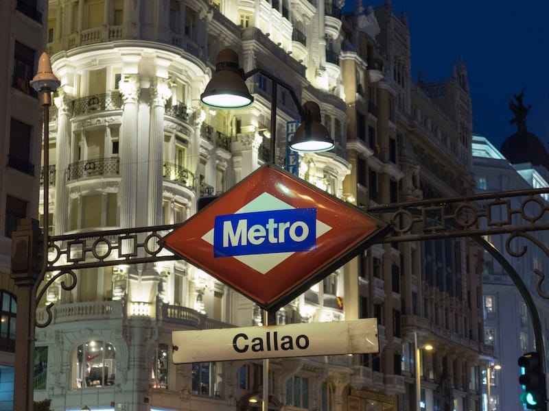 Red and white metro sign in central Madrid at night