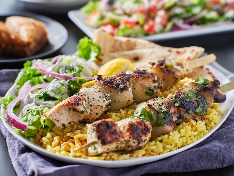 greek chicken souvlaki platter with pita bread, salad and rice